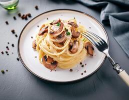A plate of spaghetti with Cabonara cream and mushroom with fork on table photo