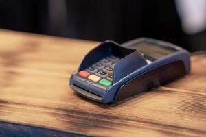 Terminal for cashless payment on a wooden background in a cafe photo