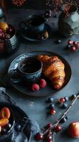 Bohemian breakfast, black aromatic coffee with a croissant and berries in stylish black dishes photo