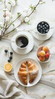 Early breakfast with black strong aromatic coffee and a croissant, complemented by fresh berries and flowers in white dishes photo