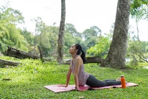 Young Woman Practicing Yoga Outdoors in a Serene Garden Setting, Relaxing and Connecting with Nature on a Sunny Day photo