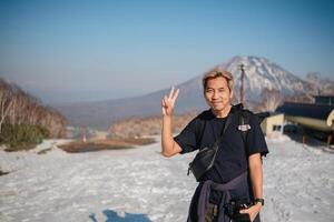 Smiling man with camera posing on snowy mountain. Concept of travel and photography photo