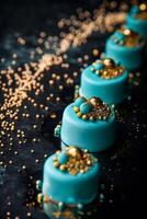 An elegant line of turquoise mini cakes adorned with gold details, on a dark background with gold sprinkles. dessert arrangement is ideal for luxury event promotions or high end culinary publications. photo