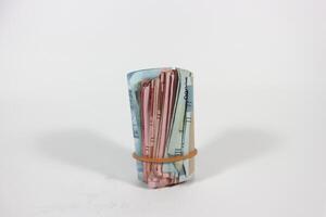 A packet of several rupiah bills is folded in half and tied with a rubber band. Bundle isolated on white background with clipping path. photo