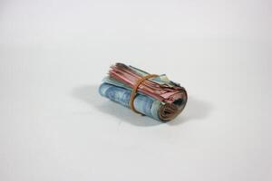 indonesian rupiah banknotes rolled into a tube and tied with a rubber band. Money roll isolated on a white background photo