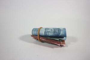 indonesian rupiah banknotes rolled into a tube and tied with a rubber band. Money roll isolated on a white background photo