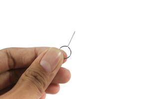 Hand Holding a SIM card ejector pin isolated on white background. photo
