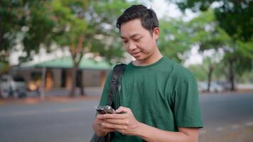 Smiling man cheats on phone while relaxing in summer park video