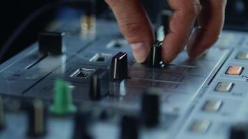 Close-up of the hands of the DJ carefully adjusting the fader on the mixer console during the live set. Musician is playing music on the controller video