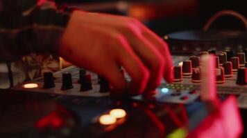 DJ cheerfully adjusting the knobs of the mixer during the party with the color concert light. Musician is playing music on the controller close up video