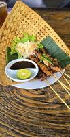 Chicken grilled satay skewers served with lime and peanut sauce on black, top view. Asian thai style food. photo