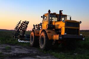 Cultivator on agricultural field at golden hour. Machine in field at sunset. photo