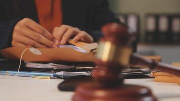 justice and law concept. asian woman lawyer working and judge in a courtroom the gavel, working with tablet and laptop and digital tablet computer on white table video
