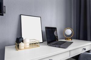 Desk with a laptop, candles, a blank picture and a table lamp in the form of a ball photo