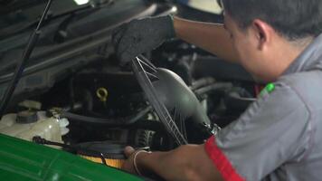 A man is working on a car engine, replacing the air filter. Concept of diligence and attention to detail, as the man carefully removes the old filter and installs the new one video