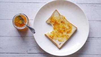 orange fruit spread on a bread on table video