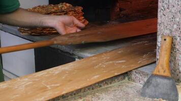A baker expertly bakes flatbread in a brick oven, showcasing craftsmanship and dedication video