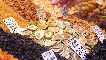 Hand selecting dried fruits in a lively market with a mix of nuts and snacks on display video