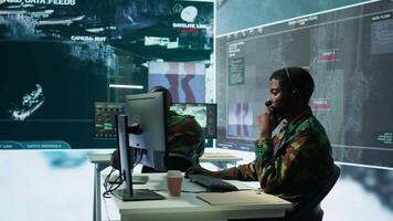Army professional in uniform works in a mission control center, coordinating surveillance systems and processing intelligence data for operations. Ensuring strategic planning and defense. Camera B. video