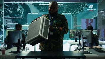 Military expert in a control center uses advanced technology and gear to gather intelligence from satellite imagery and surveillance systems. Using laptop to communicate information. Camera B. video