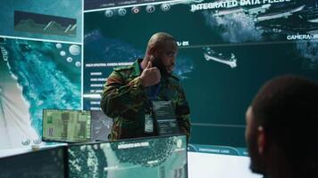 Military officer leads cybersecurity efforts in a high tech control center, ensuring data protection and managing surveillance systems, Coordinating national security operations. Camera B. video