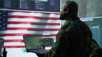 Intelligence officers in american military uniforms work on computers in a command post, managing surveillance and data analysis. Support global operations for the US government. Camera B. video