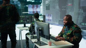 Military team in a control center uses advanced technology to gather crucial information, satellite surveillance systems to support strategic planning. Potential threats on big screen. Camera B. video