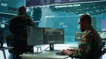Military specialist in a high tech control center managing satellite radar surveillance, collecting intelligence on cctv systems. Interpreting real time data to ensure national defense. Camera B. video