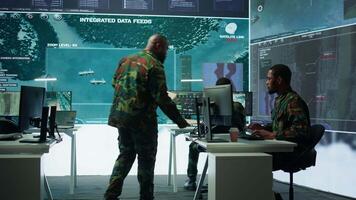 Military team operating in a high tech command post control tower, focusing on surveillance tactics for intelligence gathering. Data protection to manage critical information operations. Camera B. video