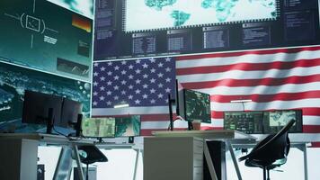 Empty army command center with big data presents the American flag, top secret armed forces agency protecting the country from threats. Monitoring room with high tech gear. Camera B. video