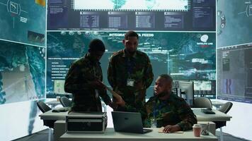 Military personnel in a modern command center handle critical information, collecting live surveillance data to maintain security protocols. Team of army crew working on reconnaissance. Camera B. video