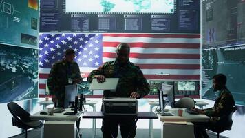 Military officer in a high tech control center engages in cybersecurity operations, protecting classified data from threats and managing digital warfare strategies to maintain state secrets. Camera B. video