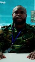 Vertical Military officer participates in a secure videoconference call in modern command center, transmitting live satellite information. Federal collaboration for national security operations. Camera A. video
