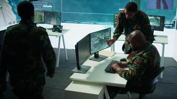 Military staff in a modern operations hub handling critical information collected on satellite systems, real time data helping support field missions. Army protocols for national security. Camera B. video