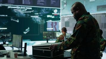 Army espionage specialist in a control center collecting satellite cctv data real time surveillance, strategic military operations. Working to ensure national security and protocols. Camera B. video