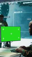 Vertical Soldier analyzing real time data next to green screen in high tech military office, processing intelligence for field operations and coordinating strategic missions to ensure national interests. Camera B. video