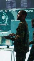 Vertical Military officers work in a high tech army control tower base, managing surveillance imagery from cctv satellite. Soldiers handle data protection to ensure national security. Camera B. video