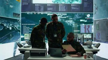 In a high tech military office, soldiers team analyze real time data collected by surveillance system. Staff interpret intelligence and coordinate operations to ensure national defense. Camera B. video