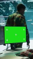 Vertical Military expert handles satellite cctv data next to mockup screen, working in a base of operations with high tech gear to support important defense missions. Coordinates strategic tactics. Camera B. video