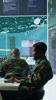 Vertical High tech military office with soldiers analyzing real time data, processing intelligence information and coordinating strategic operations to support army field missions effectively. Camera B. video