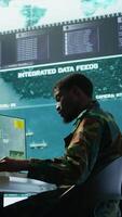 Vertical Military personnel in a control center working on data processing, integrating real time surveillance and security protocols essential for national defense and strategic operations. Camera B. video