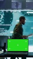 Vertical Military IT specialist in command center working on collecting field data, process real time surveillance footage and imagery for successful defense operation. Isolated mockup display on pc. Camera B. video