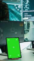 Vertical Soldier gathering real time surveillance data next to mockup display in high tech command center, processing intelligence for field operations. Working with modern gear and big screen. Camera B. video