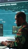 Vertical Military specialist in a high tech control center managing satellite radar surveillance, collecting intelligence on cctv systems. Interpreting real time data to ensure national defense. Camera B. video