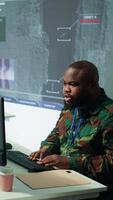 Vertical Military team in a control center uses advanced technology to gather crucial information, satellite surveillance systems to support strategic planning. Potential threats on big screen. Camera B. video