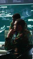 Vertical IT analyst managing satellite radar systems in modern control tower, overseeing intelligence activities and interpreting real time data. National interests for a defense mission. Camera B. video