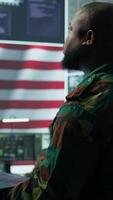 Vertical Intelligence officers in american military uniforms work on computers in a command post, managing surveillance and data analysis. Support global operations for the US government. Camera B. video