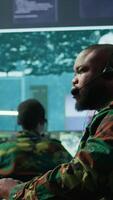 Vertical Government intelligence officer in high tech command post oversee satellite data, real time surveillance footage via radar cctv and coordinate operations. Protecting national interests. Camera B. video