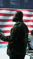 Vertical American military intelligence officers in a command center monitoring surveillance information in order to safeguard state secrets. Managing security in an army base of operations. Camera A. video