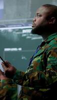 Vertical American military intelligence officers in a command center monitoring surveillance information in order to safeguard state secrets. Managing security in an army base of operations. Camera A. video